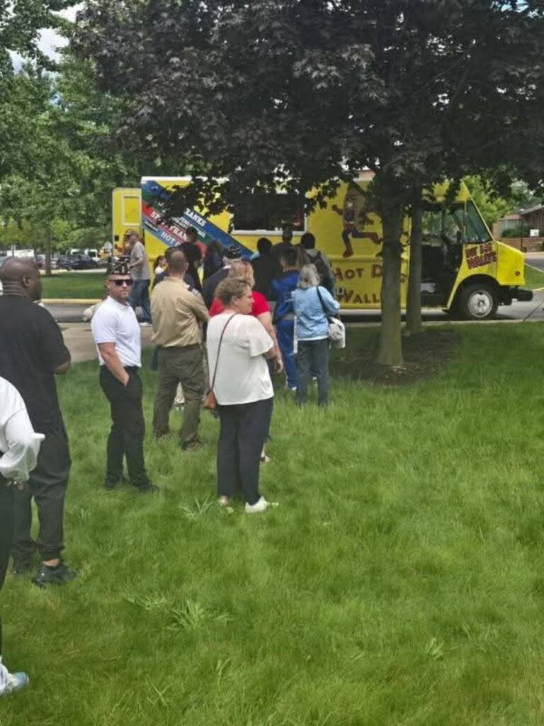 Guests lined up at the Wallys Catering food truck during an outdoor community event